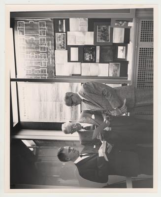 Tom Seay, Thomas Bryant, and Dean Welch of the Agriculture Department are in front of a display in the library foyer which was mounted the by Bureau of Source Material in Higher Education, later named the University Archives