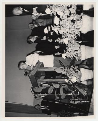 President Frank Dickey (second from right) and others stand on stage listening to Governor Bert Combs at the Medical Center dedication in Memorial Hall