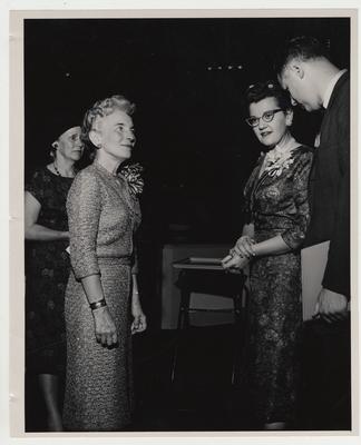 Mrs. Willard (left foreground), and Dean Drake (right) converse with two unidentified women