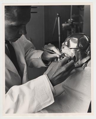 A dentistry student practicing on a mannequin
