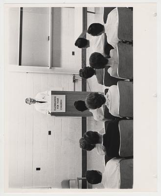 An unidentified man speaks to a group regarding 