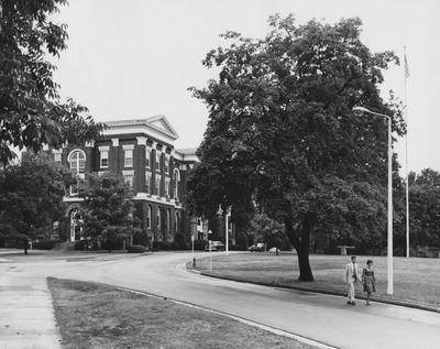 Side and front entrance of Administration Building, students walking down circle in front; photographer:  R. R. Rodney Boyce & Associates; photo appears on page 102 in Hail Kentucky