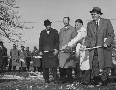 Left to right : Frank Welch, Dean of the College of Agriculture and Kentucky Governor Bert Combs (in white trench coat), shoveling while unidentified people watch at the groundbreaking of the Agricultural Science Building (Ag. Science North); Public Relations photo