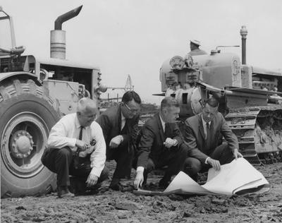 UK officials look over plans for the new Agricultural Science Building (Ag. Science North) while on site, surrounded by heavy excavation equipment; pictured left to right are David Pritchett, Stanley Wall, University President Frank Dickey, and Robert Matthews; Public Relations photo