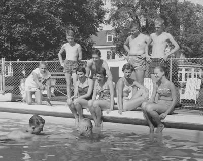 Children of Carnahan House members receive swimming instruction in the house pool; Frank J. Ogden, resident manager, in pool at right; two girls seated, third and fourth from right, are the Ades twins