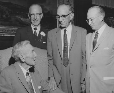 James W. Carnahan (seated, left) talking with three unidentified men at the reception for the Carnahan House dedication