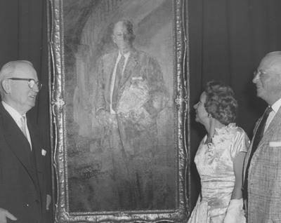 Three unidentified people look at a portrait of James W. Carnahan at the reception for the Carnahan House dedication