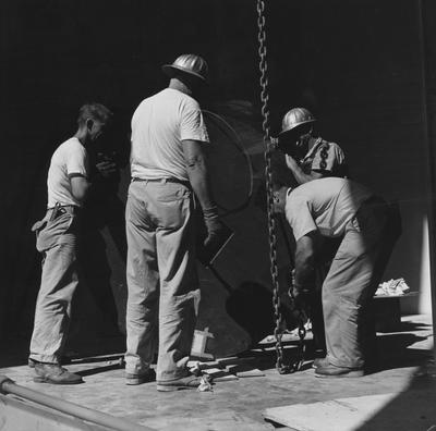 Four unidentified men installing the Van de Graff nuclear accelerator into the physics 