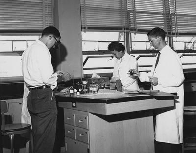 Four unidentified people are performing an experiment. This photo received December 30, 1959 from Public Relations