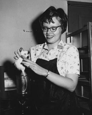 An unidentified former female student holding a rat. This photo received December 1960 from Public Relations