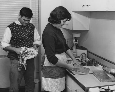Mr. and Mrs. Duke Curnette washing dishes in the kitchen of the new Cooperstown Apartments. Received on March 22, 1957 from Public Relations