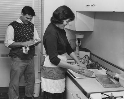 Mr. and Mrs. Duke Curnette washing dishes in the kitchen of the new Cooperstown Apartments. Received on March 22, 1957 from Public Relations