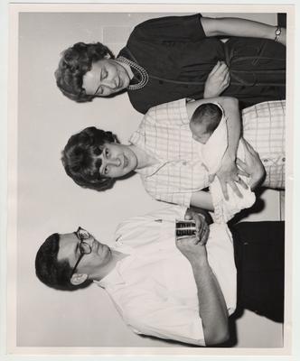 Mr. and Mrs. Archie B. Dedman and their daughter Debbie Mae (UK's first baby) stand with Mrs. Nick Kavanuagh, Hospital Auxiliary President