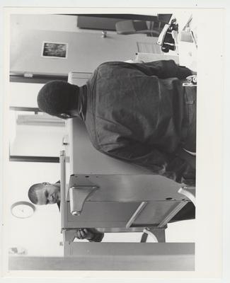 An African - American man and another man carry a desk