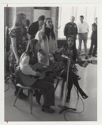 Two women with guitars singing with two other women for a group