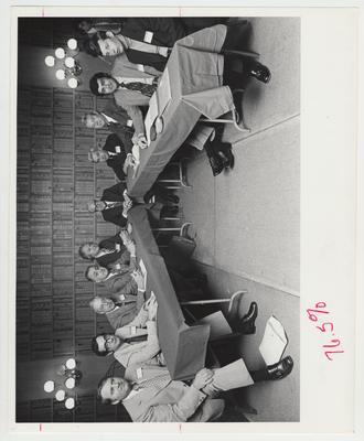 Ten men sit a tables during a meeting