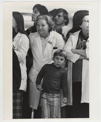A little boy stands in a crowd of Medical Center workers