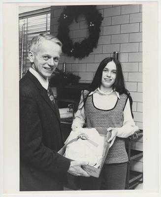 An unidentified man hands a gift to a woman