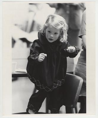 A little girl dances on a chair
