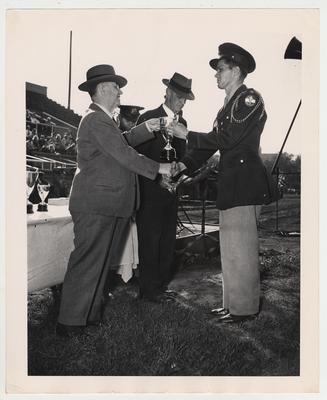 On the left, Dr. H. L. Donovan, University of Kentucky president.  In the middle, Colonel Boltos E. Brewer, former University of Kentucky professor of Military Science.  On the right, cadet Lieutenant Colonel Carl Corbin receiving the Rotary Club trophy