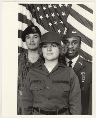 Three people in front of the American Flag.  The female's name is Edminster
