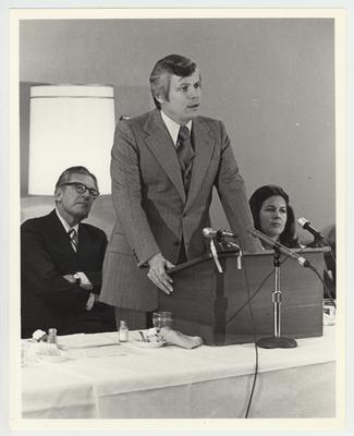The speaker in this photo is Governor John Y. Brown, Jr.  On the left is President Otis Singletary, on the right is an unidentified woman