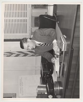 Frank Dickey seated at his desk with a pen and document in hand