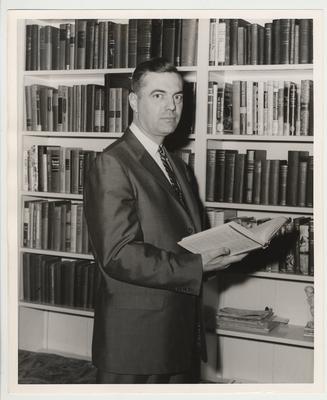 President Frank Dickey is holding a UK history book in front of a bookshelf