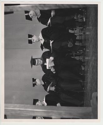 President Frank Dickey (second from the right), previous president Herman Donovan (fourth from the right) seated among unidentified men dressed in caps and gowns at Frank Dickey's inauguration ceremonies on September 24, 1957