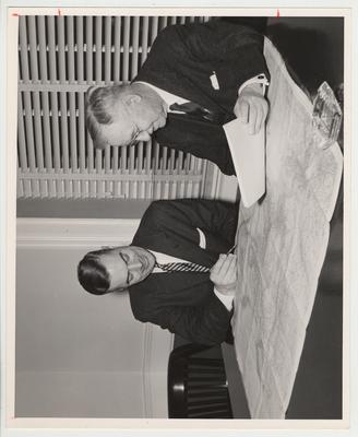 President Frank Dickey (seated left) at a table examining a map with President Emeritus Herman L. Donovan (seated right)