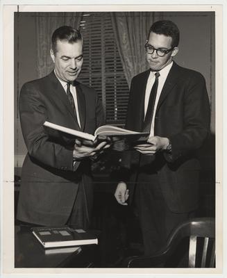 President Frank Dickey standing with an unidentified man looking at the Kentuckian (the yearbook of the University of Kentucky)
