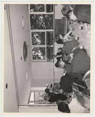 President John Oswald is seated at a table near open windows and speaking into microphones for an interview in the Student Center