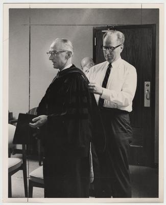 An unidentified man helps Doctor William B. Arthur (left) prepare for president Oswald's inauguration