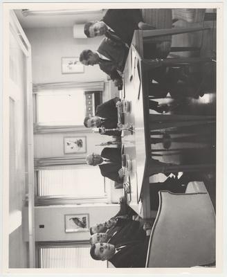 President John Oswald (third from the right) and six other unidentified members of the Executive Committee of Trustees sit around a table at a meeting in Henderson, Kentucky