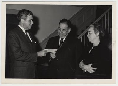 Richard Cooper (far left) handing President John Oswald (center) a check from an unknown donor as Helen King (far right) watches