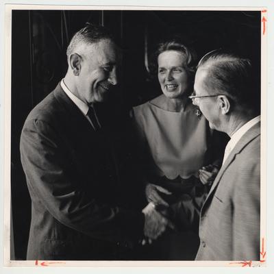 President Oswald (left) standing with his wife Rosanel (center)  and shaking the hand of an unidentified man