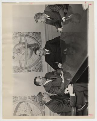 President Oswald (second from the right) seated at a table with three other men