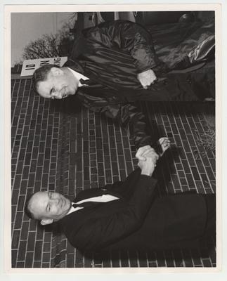 President John Oswald (standing on right) shaking hands with an unidentified man