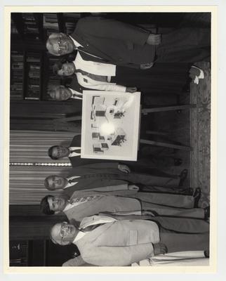 Standing around the designs for a new super computer for the University of Kentucky are : (from left to right) State Representative Louis Mack, State Senator Ernesto Scorsone, State Senator Mike Maloney, President David Roselle, State Senator Jack Trevey, State Representative Pat Friebert, and an unidentified senator