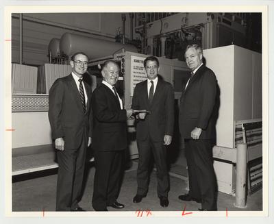 President Roselle (second from right) is standing with Mr. Bower (far right), Mr. Truscatt (second from the left) and Roger Schipke (far left) at the General Electric plant in Louisville.  Mr. Truscatt is handing President Roselle a paper