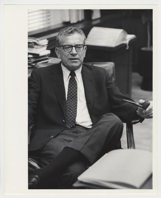 President Singletary sitting in a chair, smoking a pipe