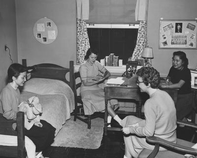 Four unidentified women are talking in a dorm room of Jewell Hall. Jewell Hall was named after Mary Frances Jewell. Received March 16, 1957 from Public Relations