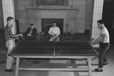 Two unidentified men watch as two unidentified men play table tennis in Bowman Hall. Received on March 18, 1957 from Public Relations