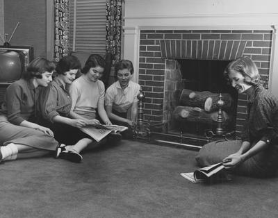 Five unidentified women are sitting in the living room, around a fire place in Boyd Hall, a woman's dormitory. Boyd Hall was built in 1925 and was named after Cleona Boyd