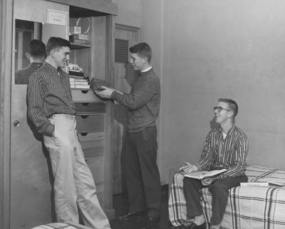 Three unidentified men are talking in a Donovan Hall dorm room