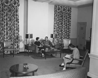 An unidentified woman and an unidentified man are talking as an unidentified woman reads in Keeneland Hall. Keeneland Hall was named after the Keeneland Foundation which donated $200,000 and on October 17, 1955, it was dedicated to the foundation. Received March 16, 1957 from Public Relations