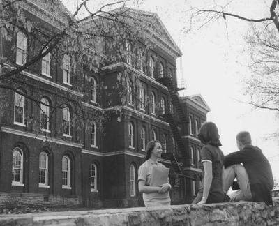 Two unidentified women and one unidentified man are talking near the White Hall Dormitory. The 