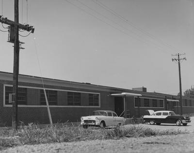 Two cars and two bikes are near the Food Storage Building. Received May 3, 1961 from Public Relations