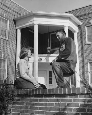 An unidentified woman in talking to an unidentified man in front of the Alpha Delta Pi House