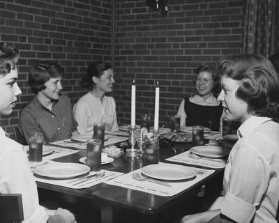 Helen Shuck (third from left), Joan Putallico (fifth from left) and three unidentified women are seated around a table in the Kappa Delta house. Received May 17, 1958 from Public Relations